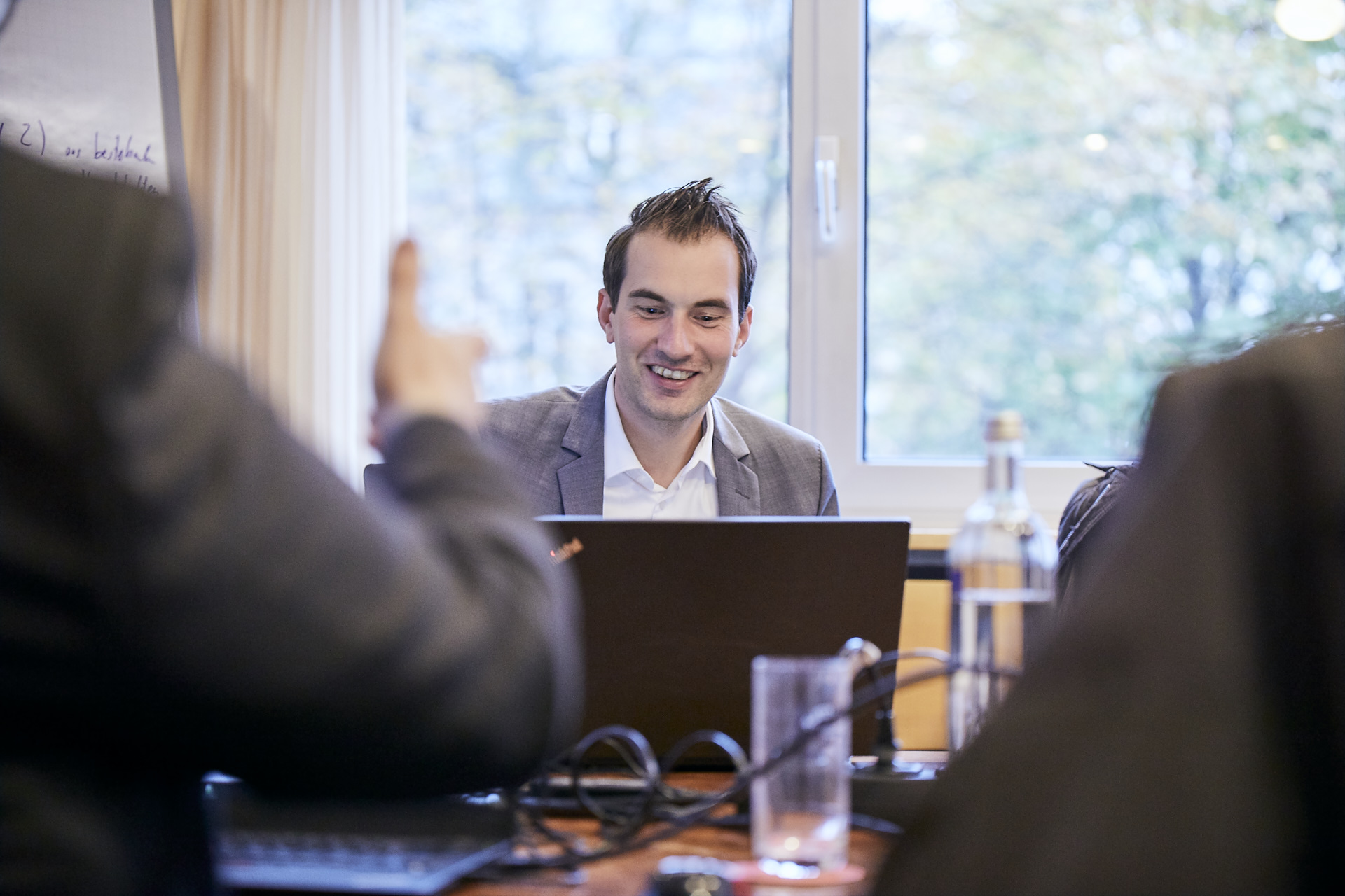 Mann sitzt bei einer Konferenz hinter seinem Laptop