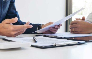 regulatorische anforderungen banken: Bücher aufeinander gestapelt mit offenem notizbuch im Hintergrund