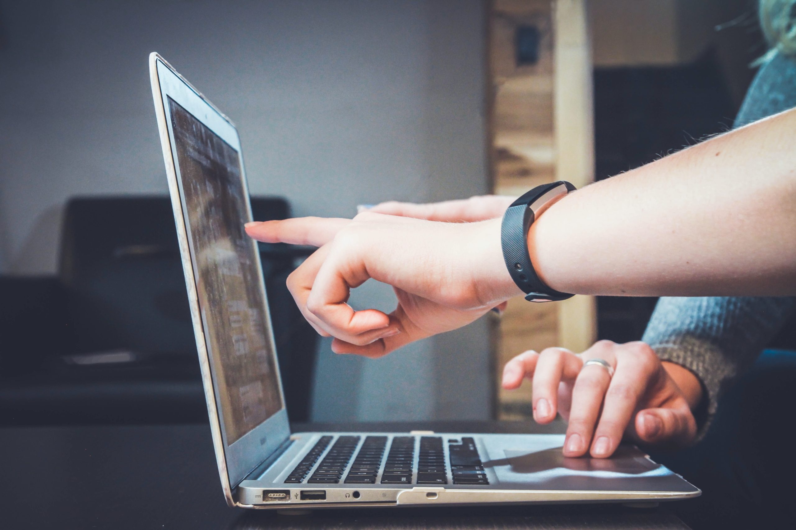 Zwei Menschen zeigen auf Laptop Bildschirm