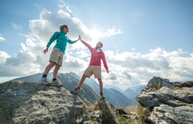 Ein Wanderpaar erreicht feiernd den Gipfel des Berges, high five