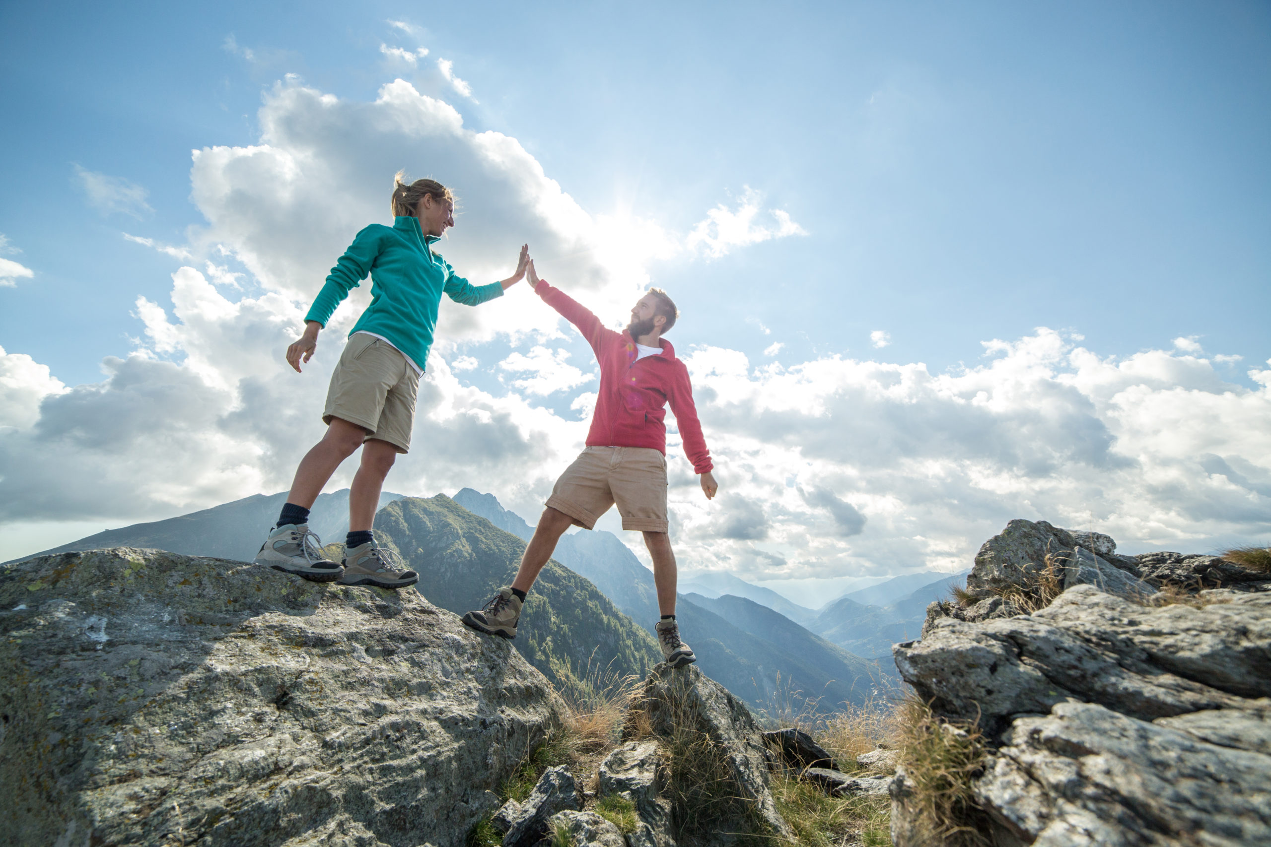 Ein Wanderpaar erreicht feiernd den Gipfel des Berges, high five