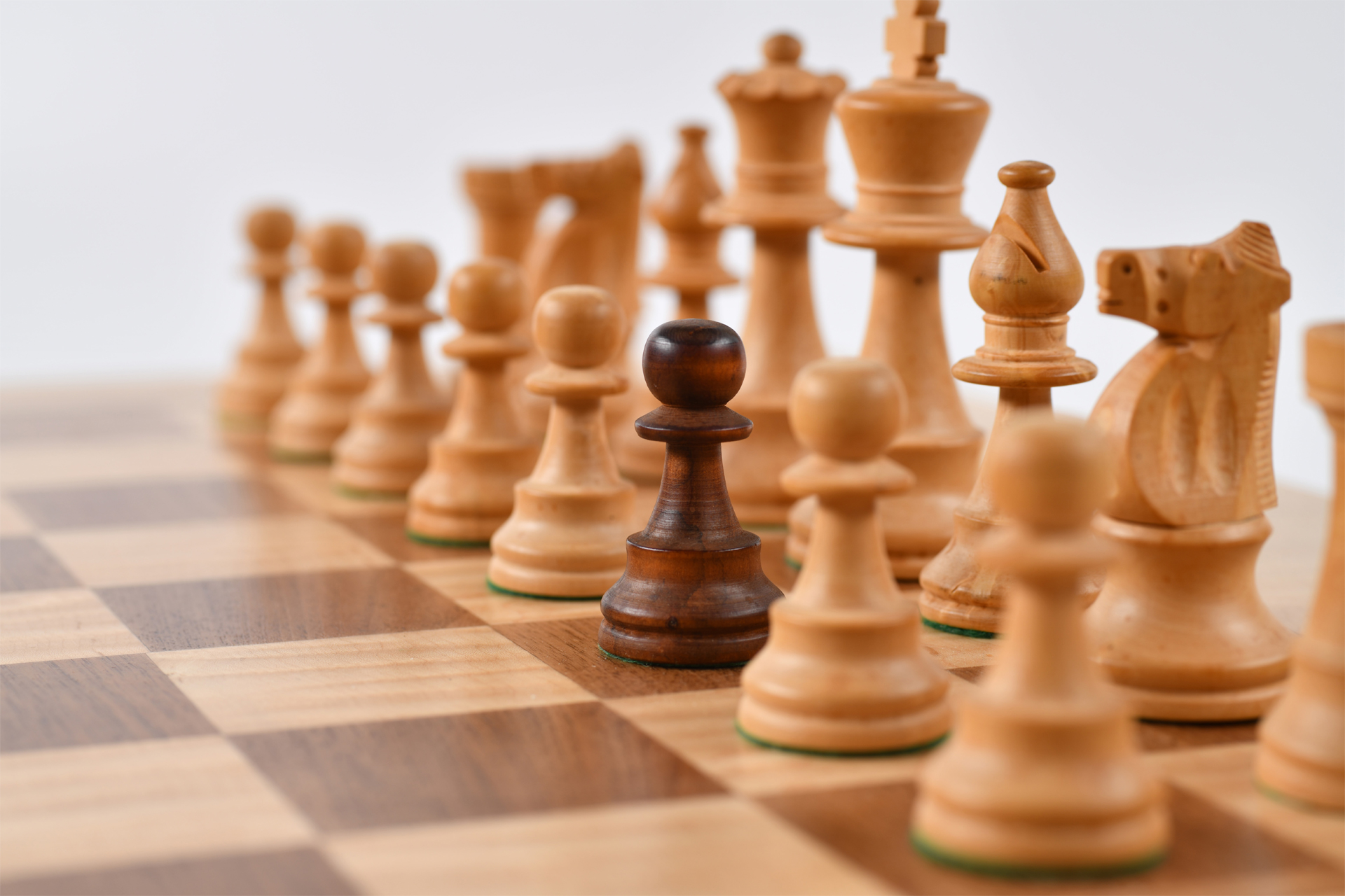 Integrationsstrategie Schachbrett mit einem schwarzen Bauer zwischen weißen Figuren