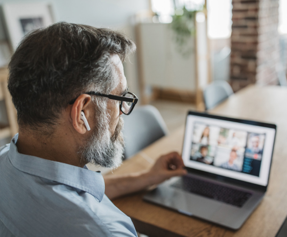 Mann mit Airpods in den Ohren beteiligt sich an einem Online Call im Home Office teilnimmh