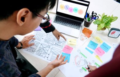 Team arbeitet an einem UX Projekt mit Zeichnungen von Ideen auf Papier und Abbildungen auf dem Laptop