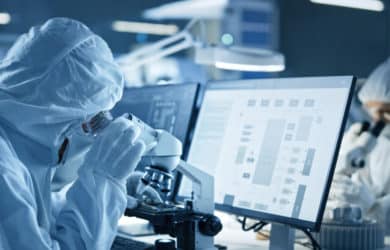 Pharma- und Medizinprodukte: Moderne Fabrik: Ein Team von Ingenieuren und Wissenschaftlern in sterilen Schutzanzügen arbeitet an Desktop-Computern, benutzt Mikroskope und entwickelt Elektronik für die medizinische High-Tech-Forschung