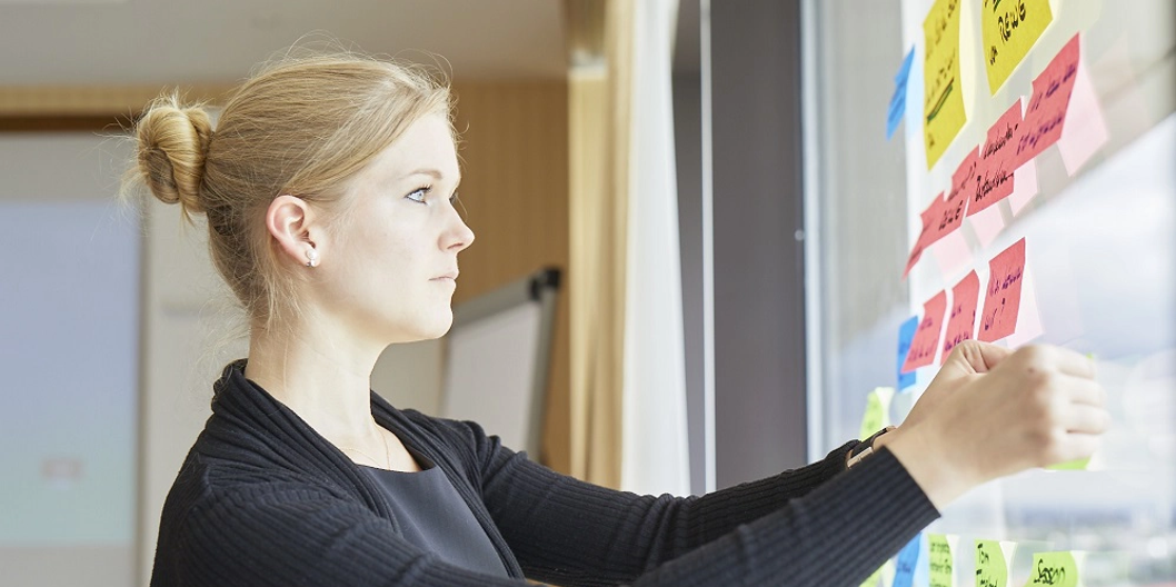 Mitarbeiterin klebt Sticky Notes an ein Fenster