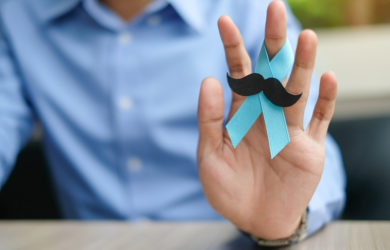 Movember. Mann mit blauer Schleife und künstlichem Schnurrbart, der das soziale Engagement von Consileon verdeutlicht