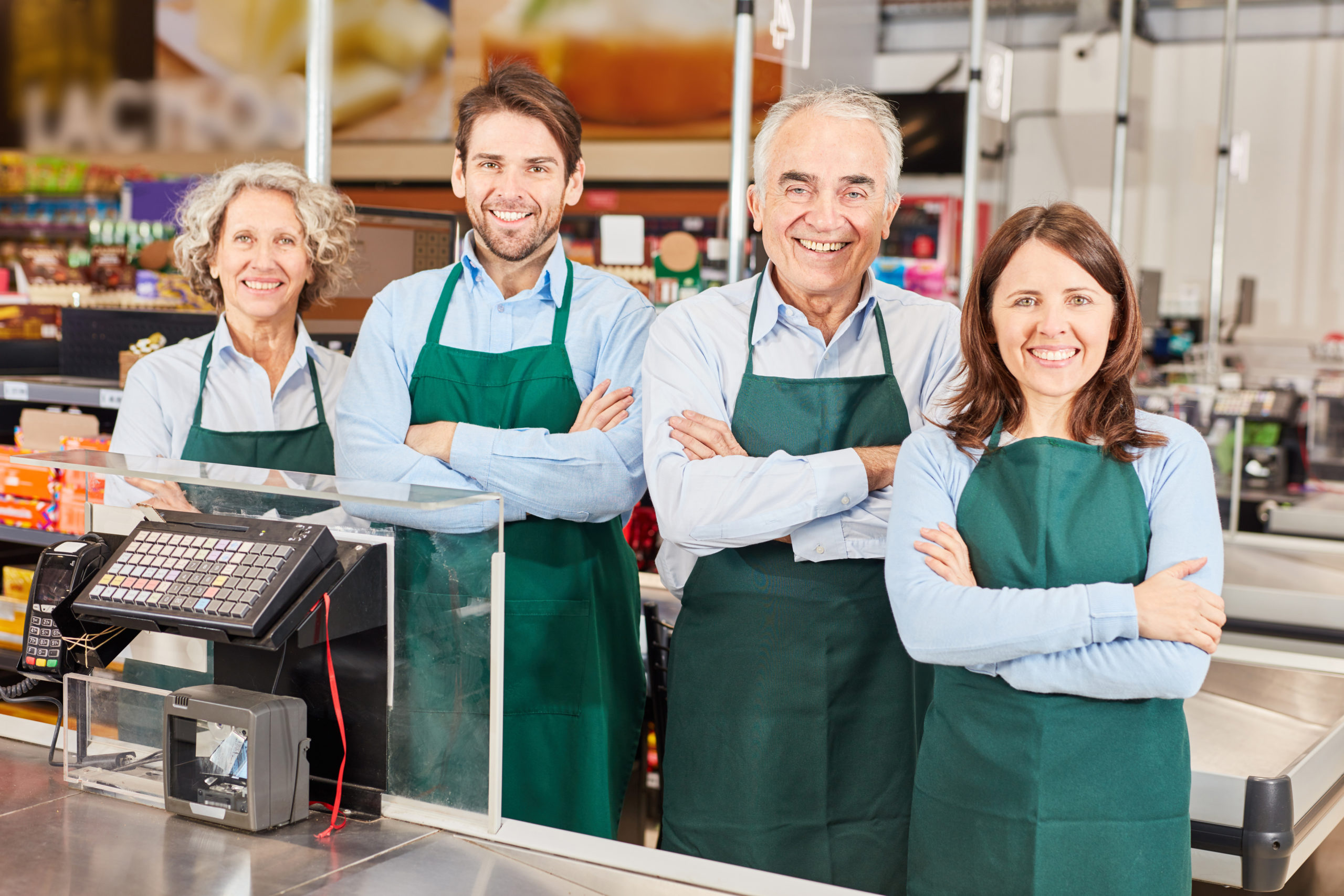 vier Arbeiter, die durch IT gestützte Personaleinsetzplanung angestellt wurden, stehen an der Kasse