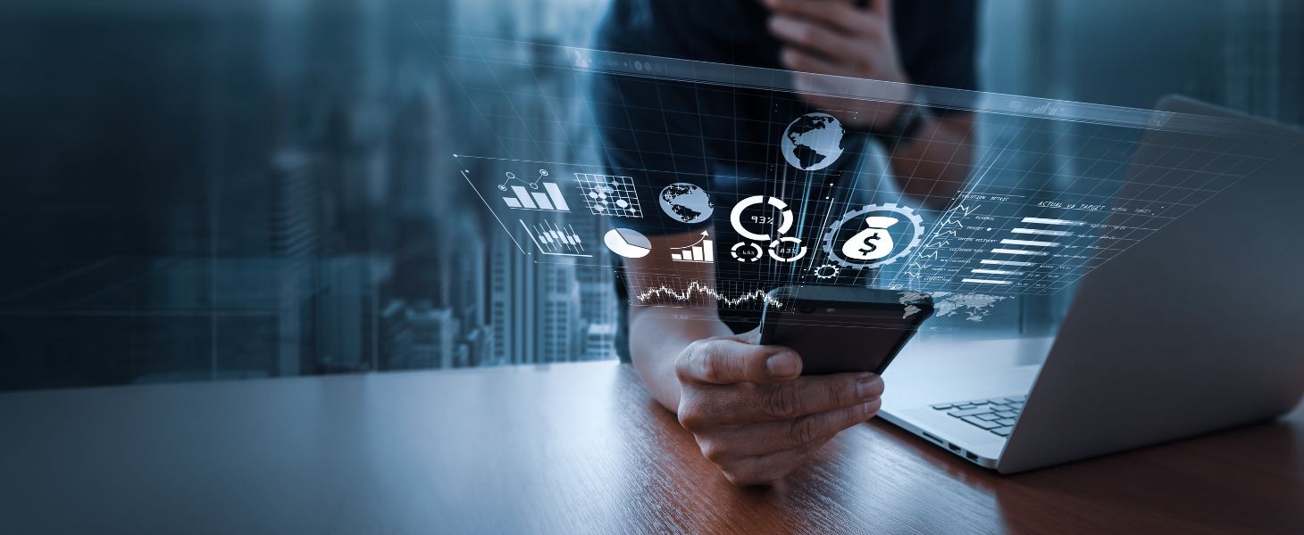 Person nutzt Smartphone und Laptop, darüber eingeblendete digitale Diagramme und Finanzkennzahlen, symbolisch für datengetriebene Analyse, digitale Geschäftsmodelle und moderne Finanztechnologie.