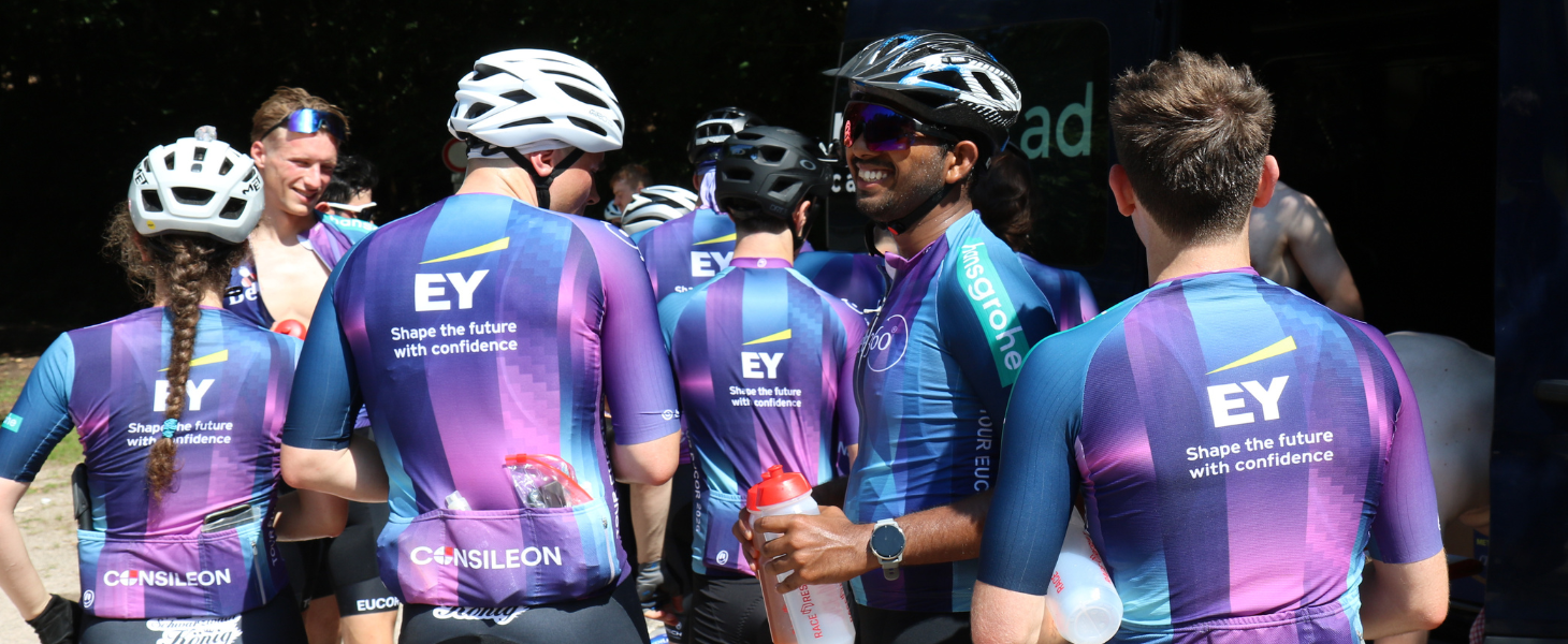 Eine Gruppe Radfahrer in gleichen Jerseys steht beisammen.